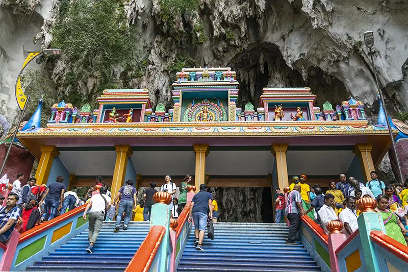 Visitors climbing colorful stairs at Batu Caves entrance during kuala lumpur excursions, a popular tourist attraction in Kuala Lumpur, Malaysia