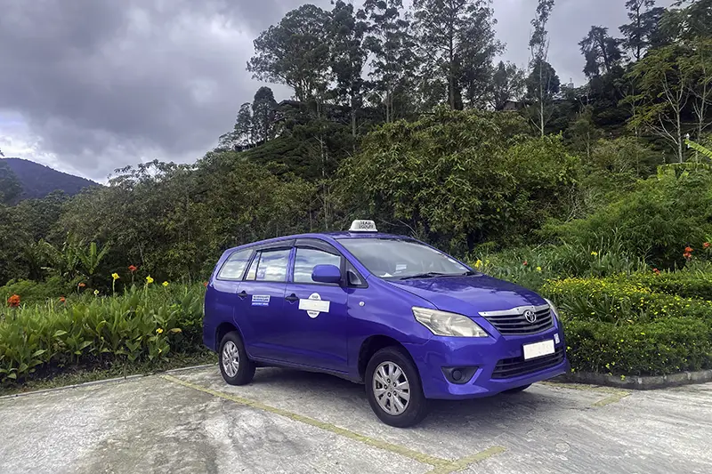 A blue taxi in Malaysia parked in a scenic area, offering a convenient option for multi-stop or en-route trips for tourists.