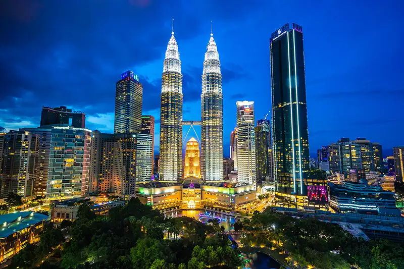 Petronas Twin Towers illuminated at night with a view of the surrounding Kuala Lumpur skyline.