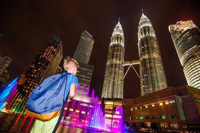 A child enjoying the colorful musical fountain show at KLCC Park, one of the top things to do in Kuala Lumpur at night, with the Petronas Twin Towers in the background.