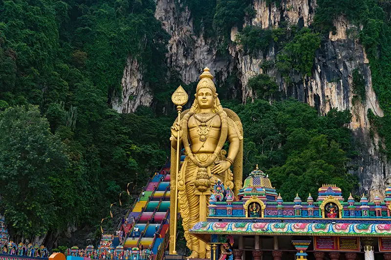 Golden Lord Murugan statue at Batu Caves with colorful temple and staircase, one of the best places to visit in Malaysia