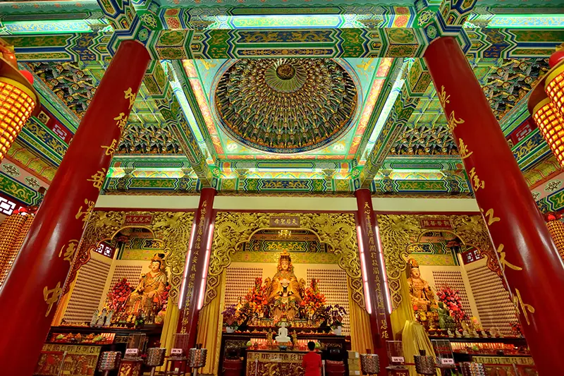 Main prayer hall of Thean Hou Temple Kuala Lumpur with ornate ceiling and red columns featuring Chinese calligraphy.