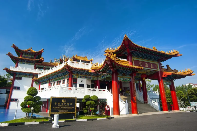 Thean Hou Temple in Kuala Lumpur with traditional Chinese architecture, red pillars, and golden tiled rooftops under a clear blue sky.